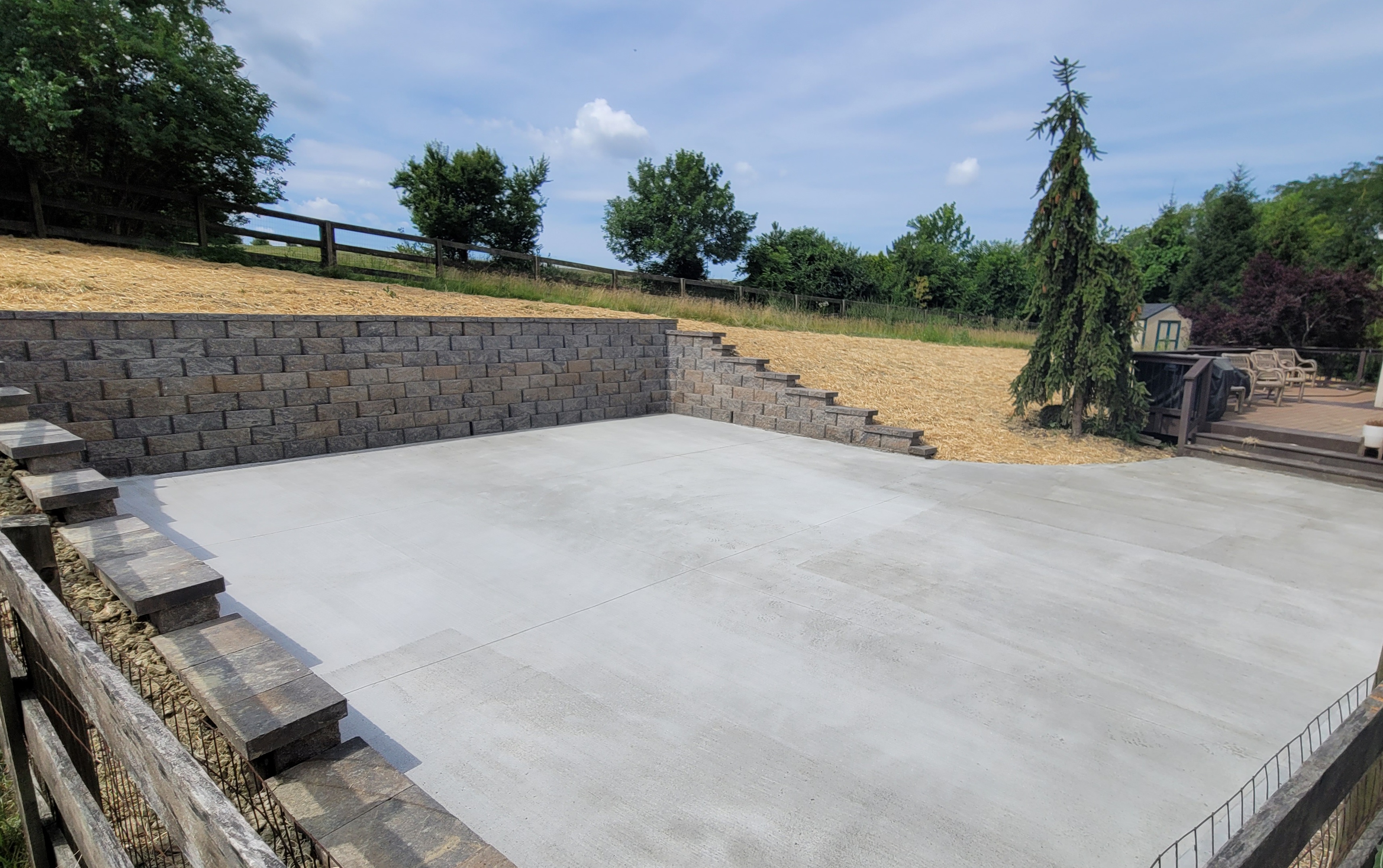 We installed a second natural stone retaining wall in West Chester. The homeowners wanted a space that would accommodate their large family but were frustrated with the persistent slope in their backyard.   To solve this, we built this Harrington retaining wall to provide a flat space in the yard perfect for games and entertainment.  